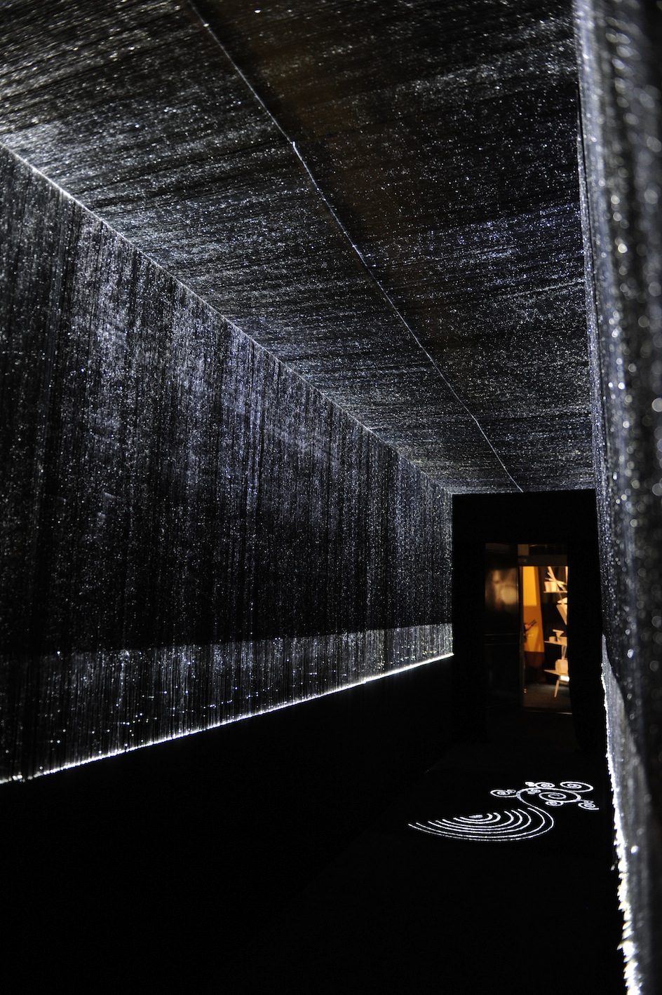 Illuminated curtain walls lining a dark corridor